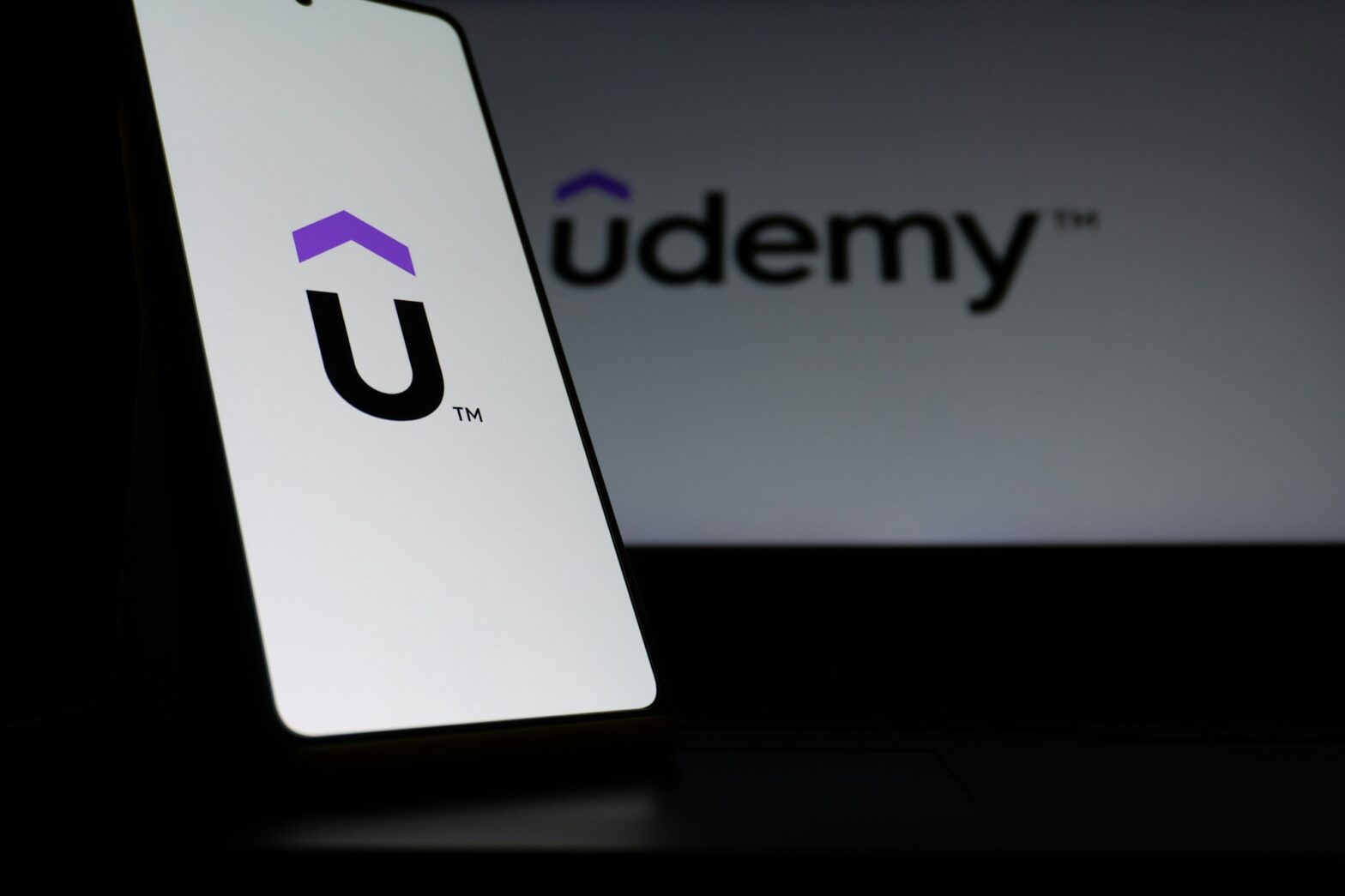 Udemy logo displayed on a smartphone screen and a laptop, illustrating online learning and course certificates